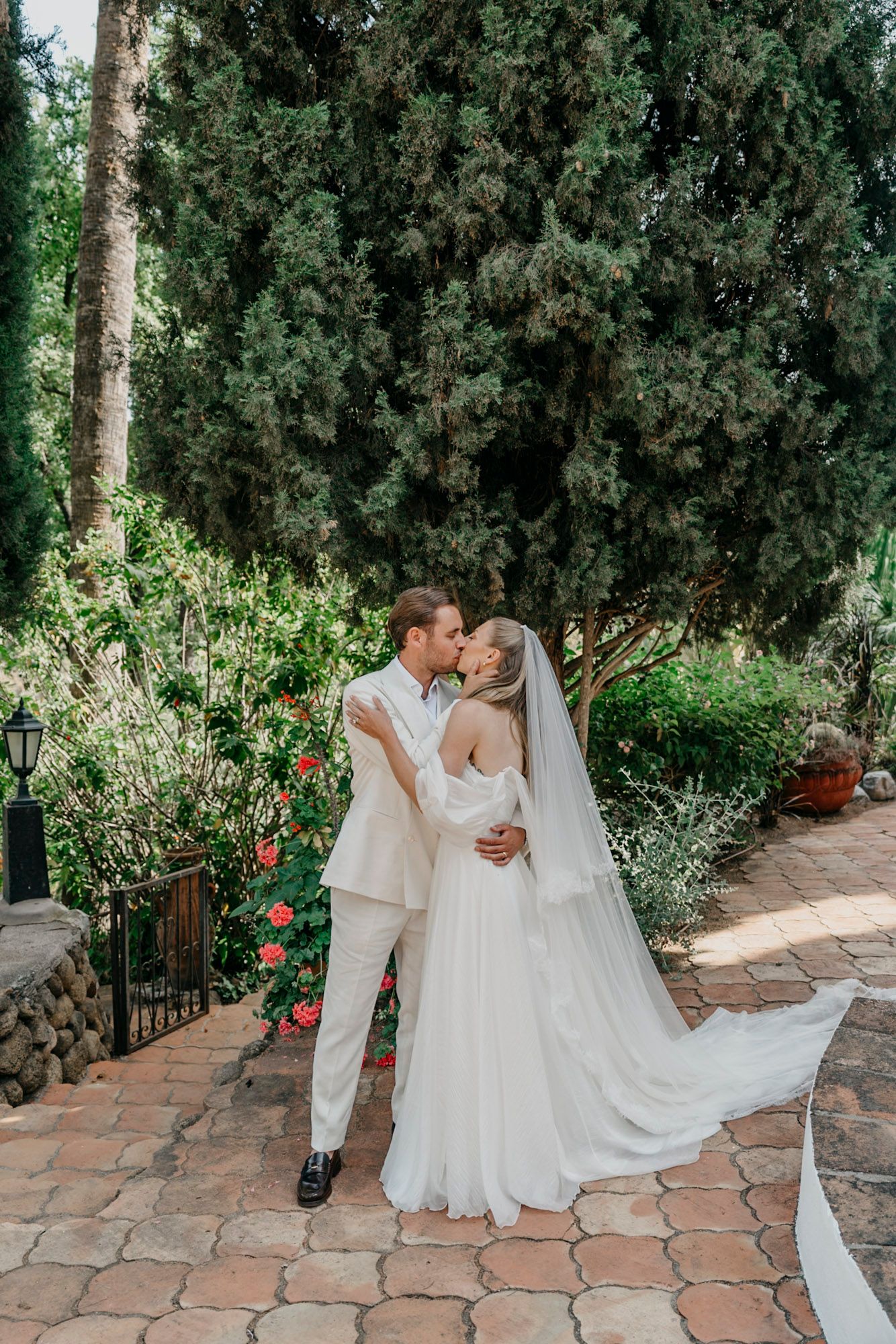 Romantic wedding portraits along cypress-lined pathway in Mediterranean garden setting.