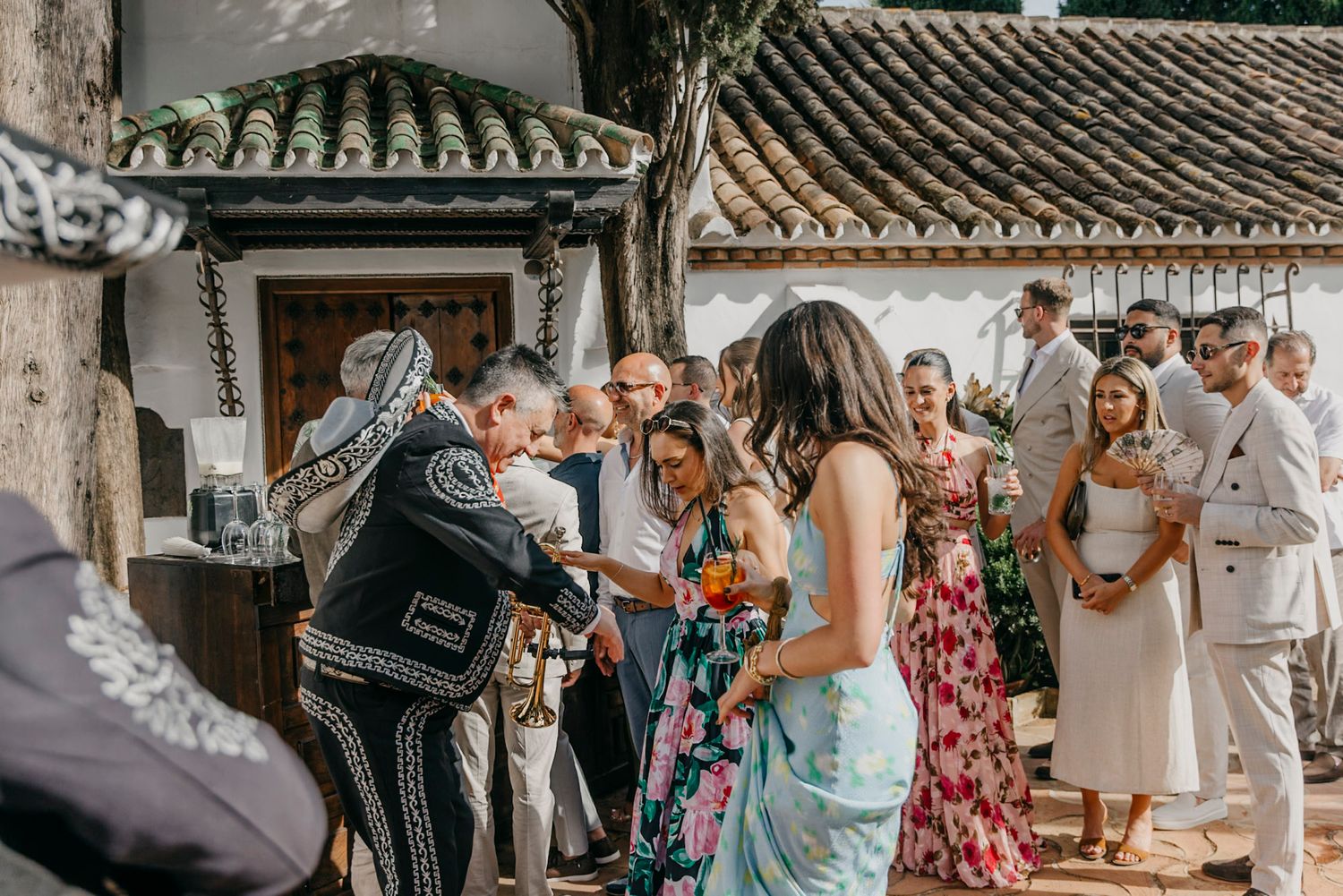 Wedding guests mingle and celebrate during outdoor reception at Mediterranean villa with traditional architecture.