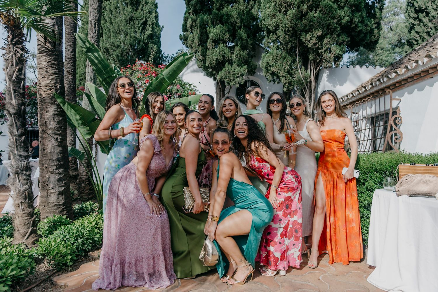 Colorful wedding party in tropical dresses posing outdoors at a Spanish-style venue.