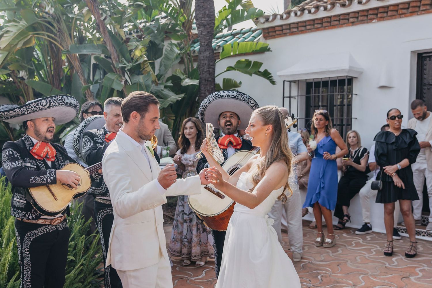 Wedding celebration with dancing and music in an outdoor Spanish colonial courtyard.
