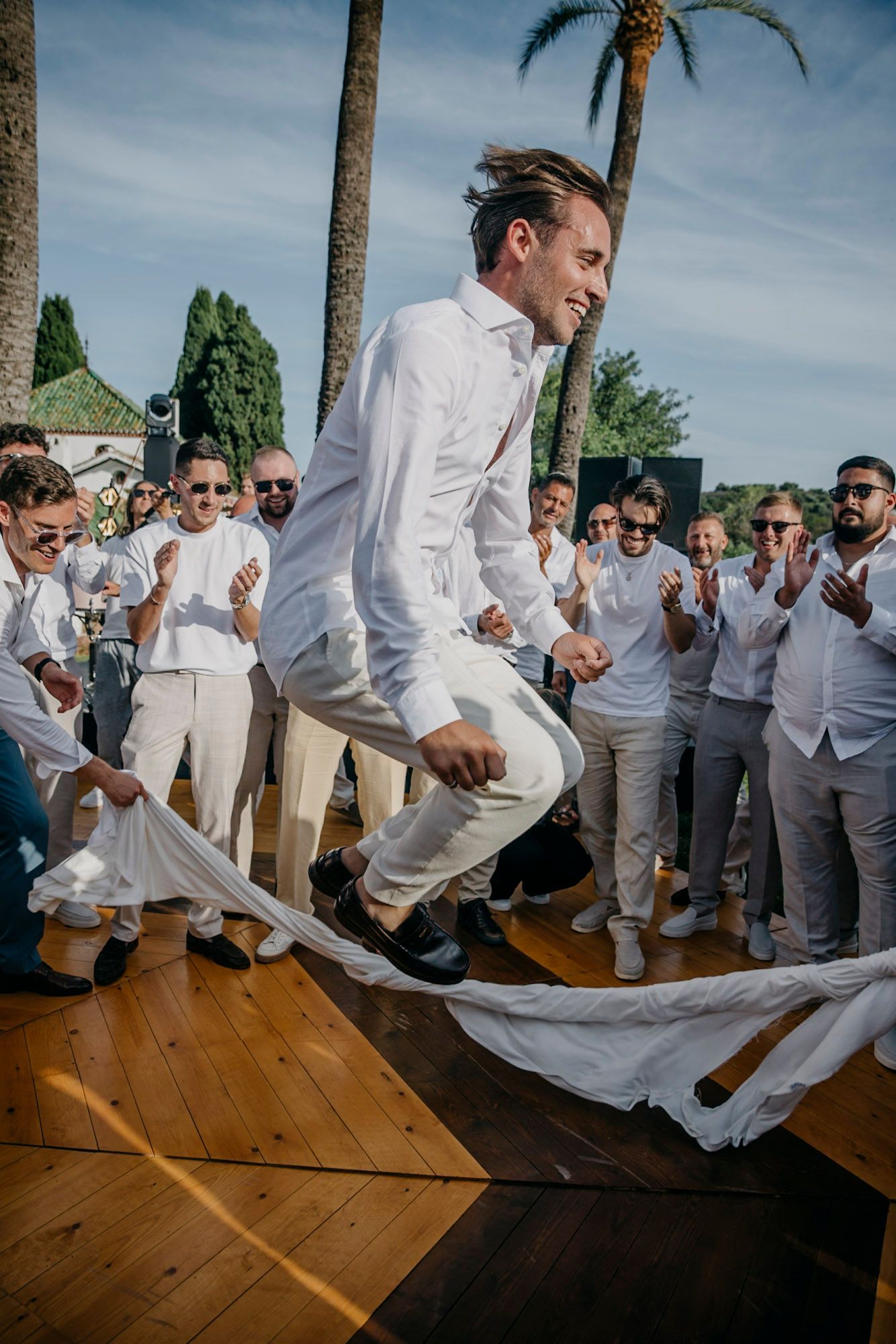 Groomsmen performing a choreographed dance routine on a wooden floor outdoors.