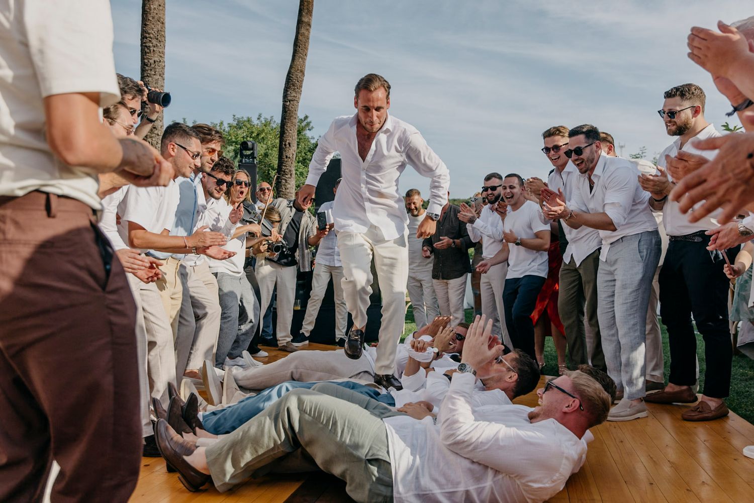 Wedding guests in white attire dance and celebrate on an outdoor dance floor.