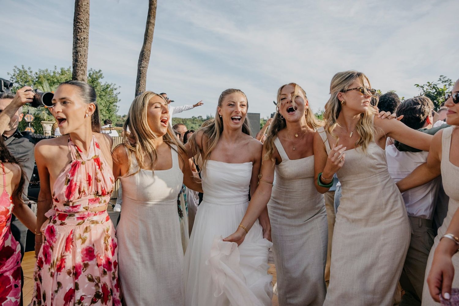 Wedding party members celebrate with joyful expressions during outdoor festivities.