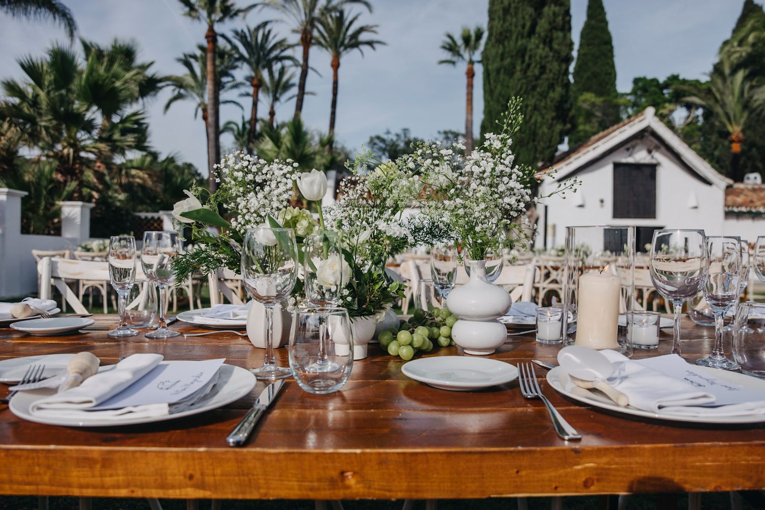 Elegant table settings with wine glasses and place settings at an outdoor wedding reception.