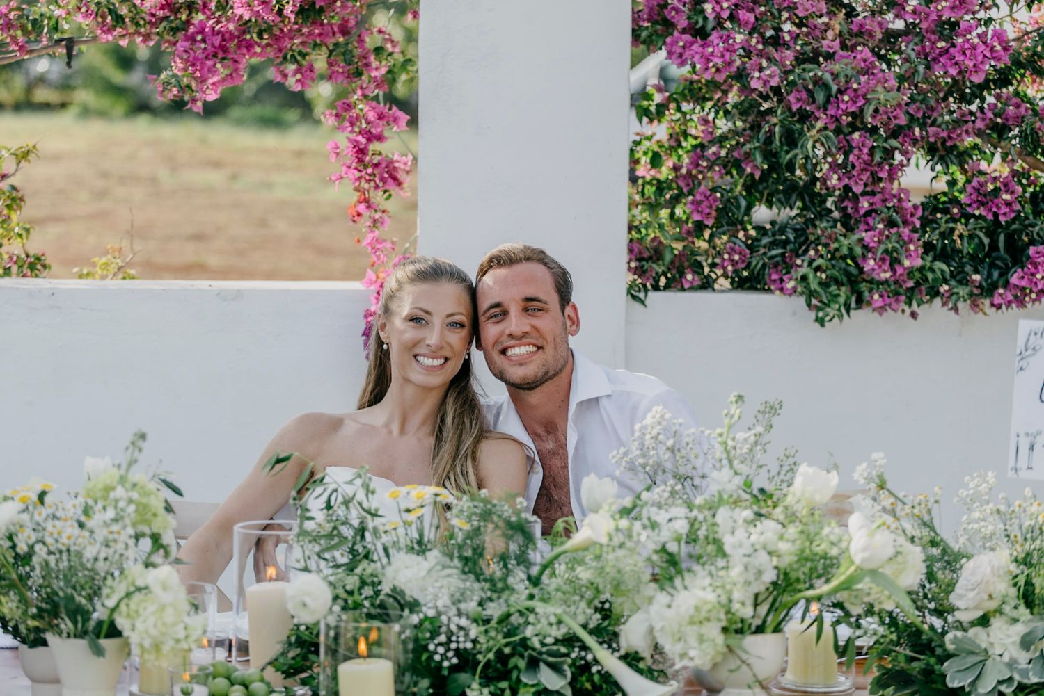 Pink bougainvillea flowers frame a white Mediterranean-style wedding venue.