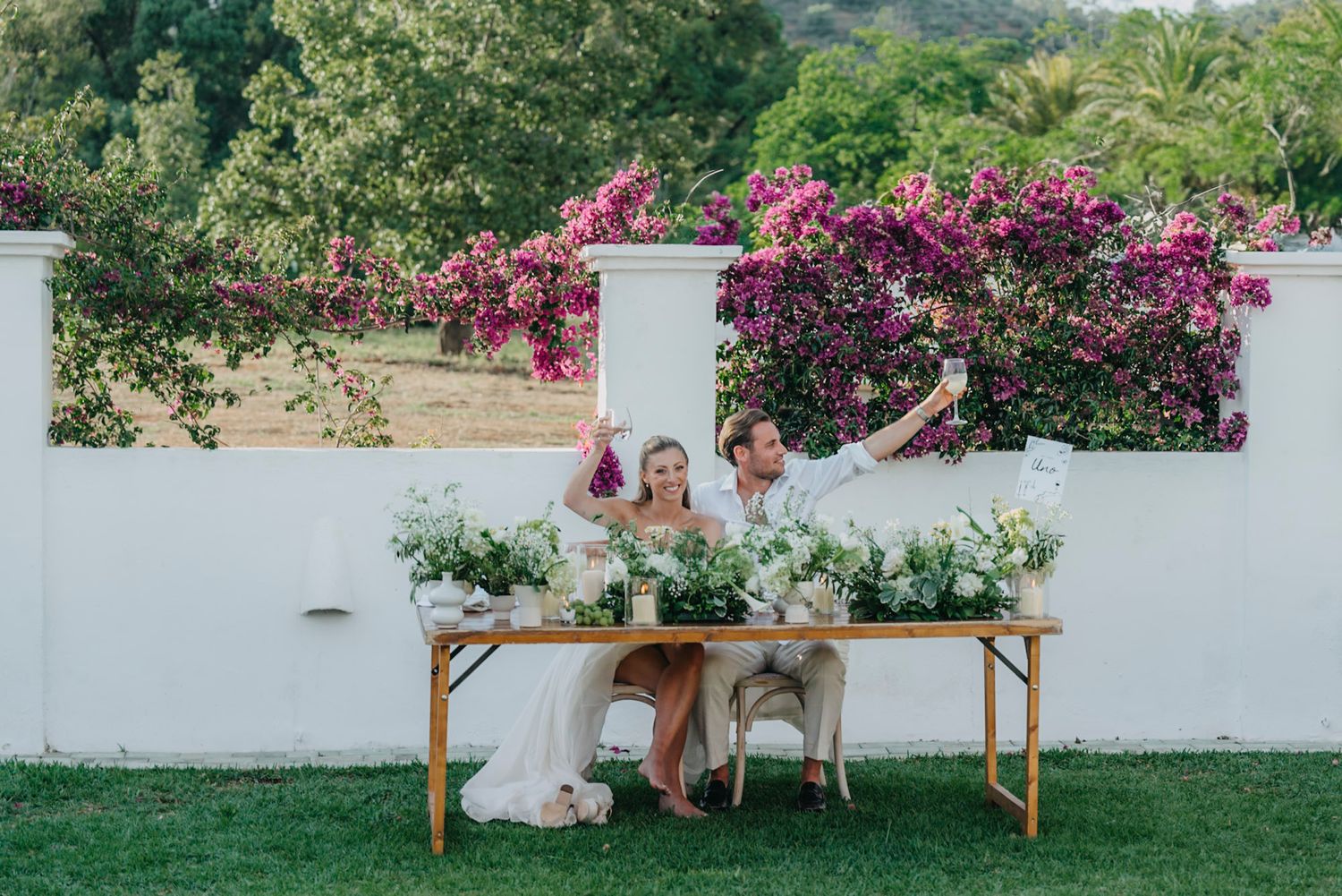 Beautiful outdoor wedding venue with white walls and vibrant pink bougainvillea flowers.