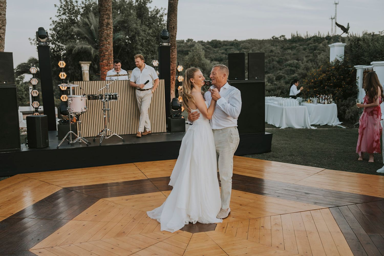 Wedding guests dance and celebrate on a wooden dance floor at an outdoor reception venue.