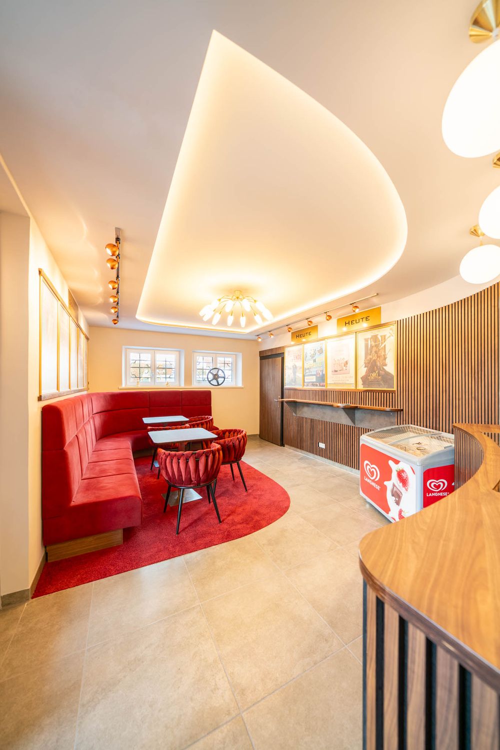 Modern office interior with curved walls, red carpet, and wooden furniture showcases sleek contemporary design elements.