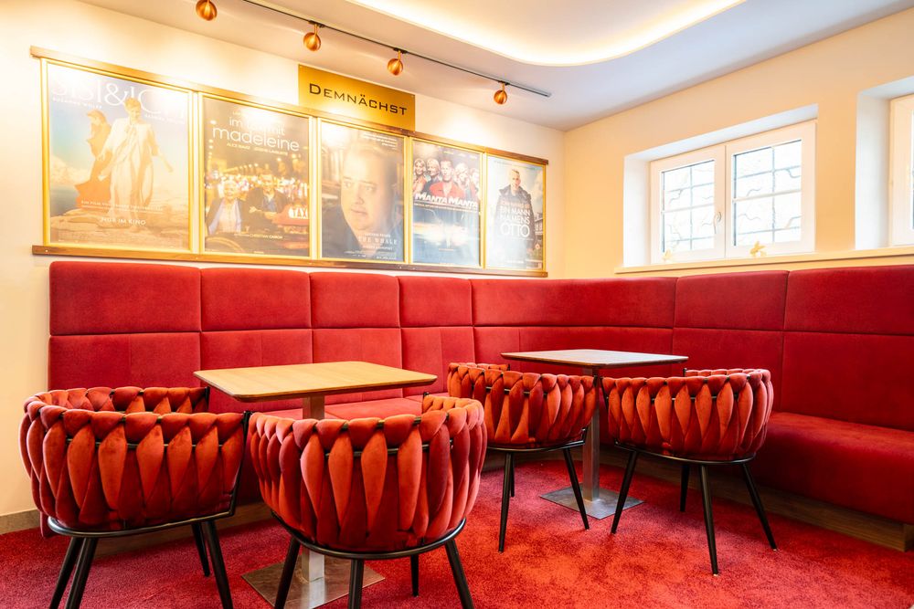 Modern restaurant interior with red leather booth seating and wooden tables in a bright dining space.