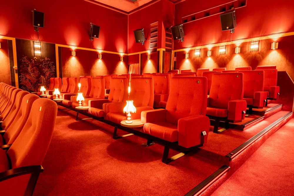 Luxurious red velvet movie theater with plush seats and warm ambient lighting creates an intimate screening atmosphere.
