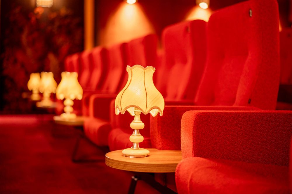 Vintage table lamps with white shades cast a warm red glow in a dimly lit room creating an intimate atmosphere.