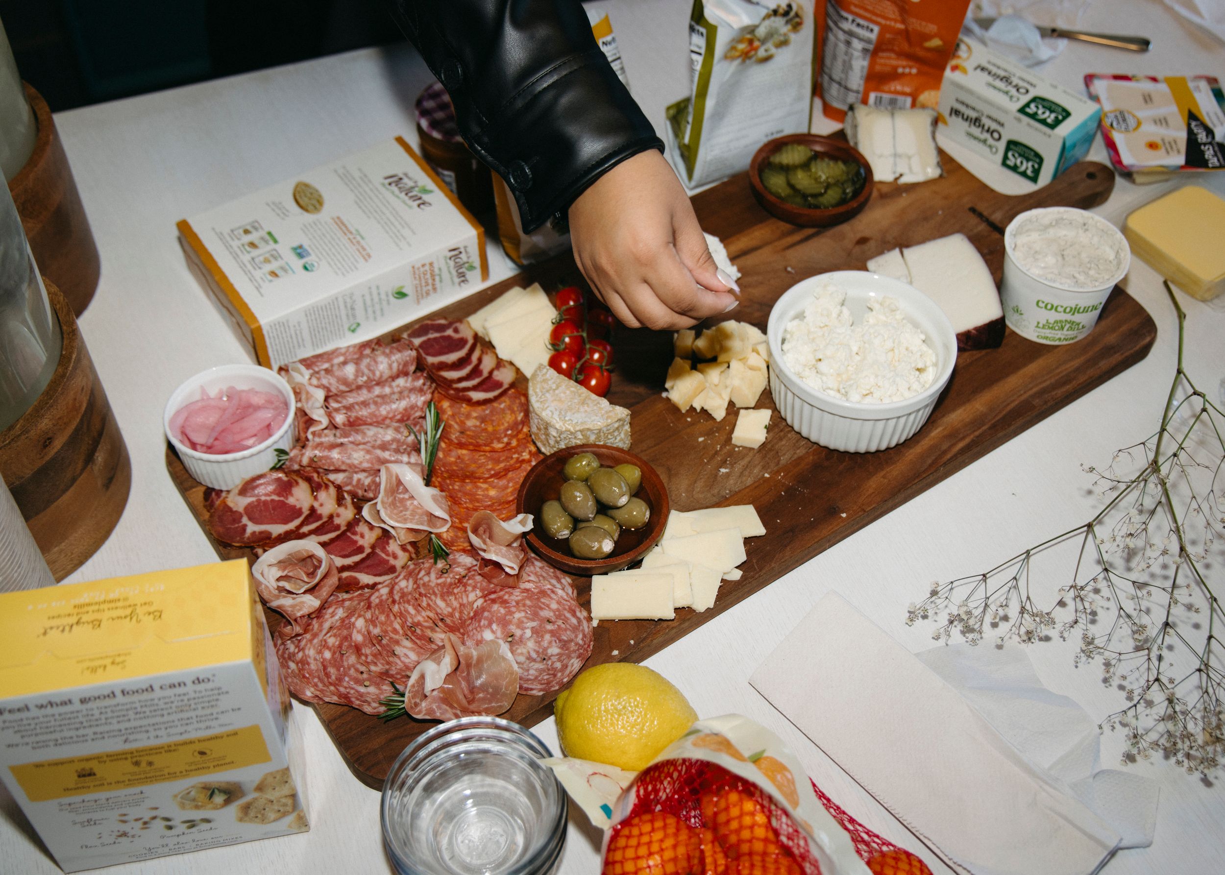 Charcuterie spread from above, hand reaching for cheese