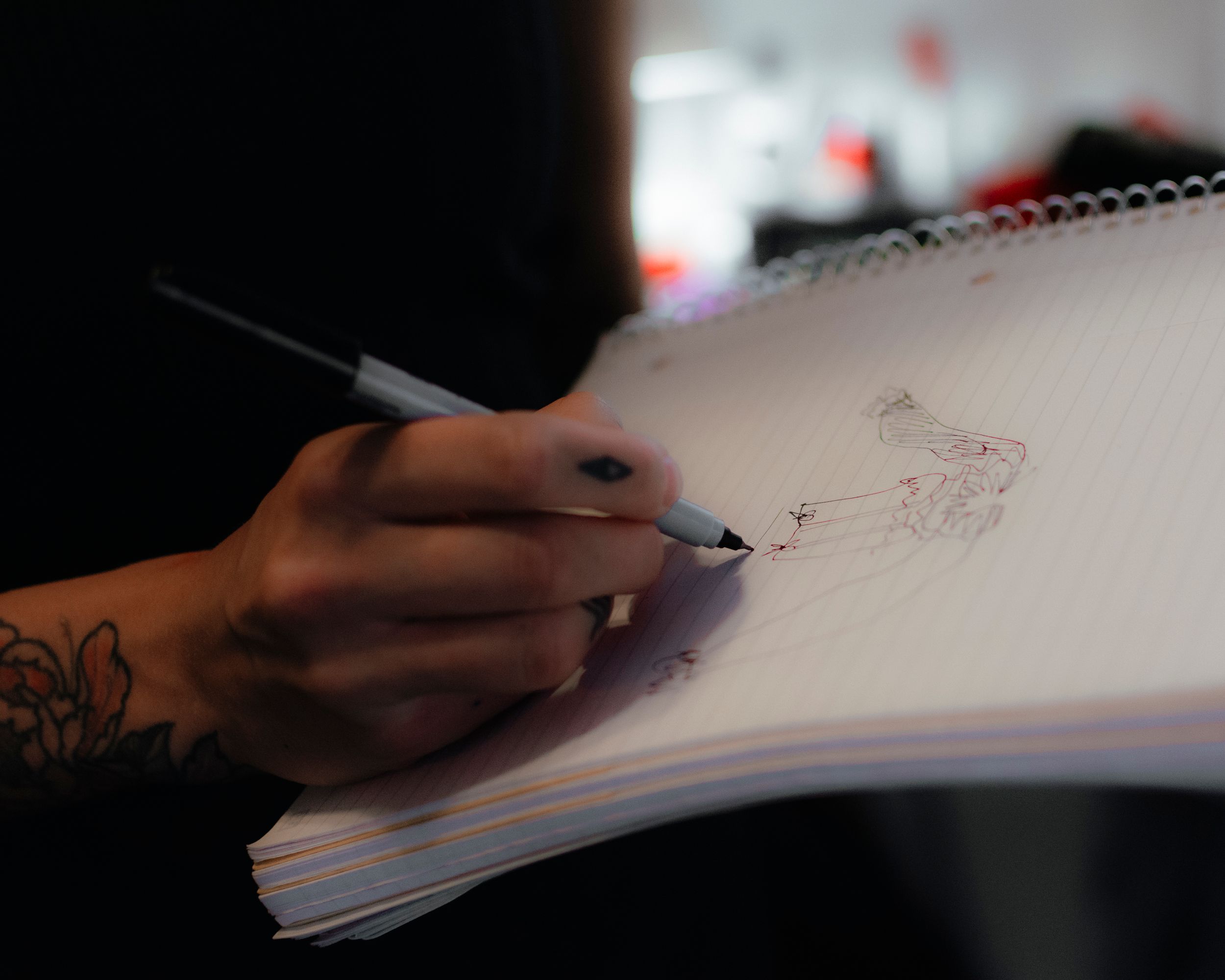 Tattooed hand drawing a sketch of a fashion design