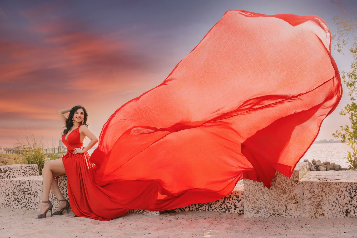 A flowing red fabric billows dramatically against a sunset sky creating an artistic movement effect.