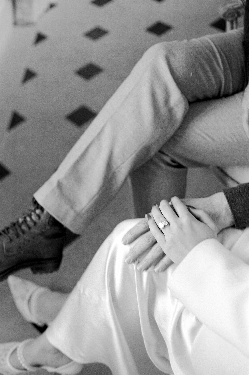 Black and white photo of someone reclining on a couch wearing white pants and lace-up boots.