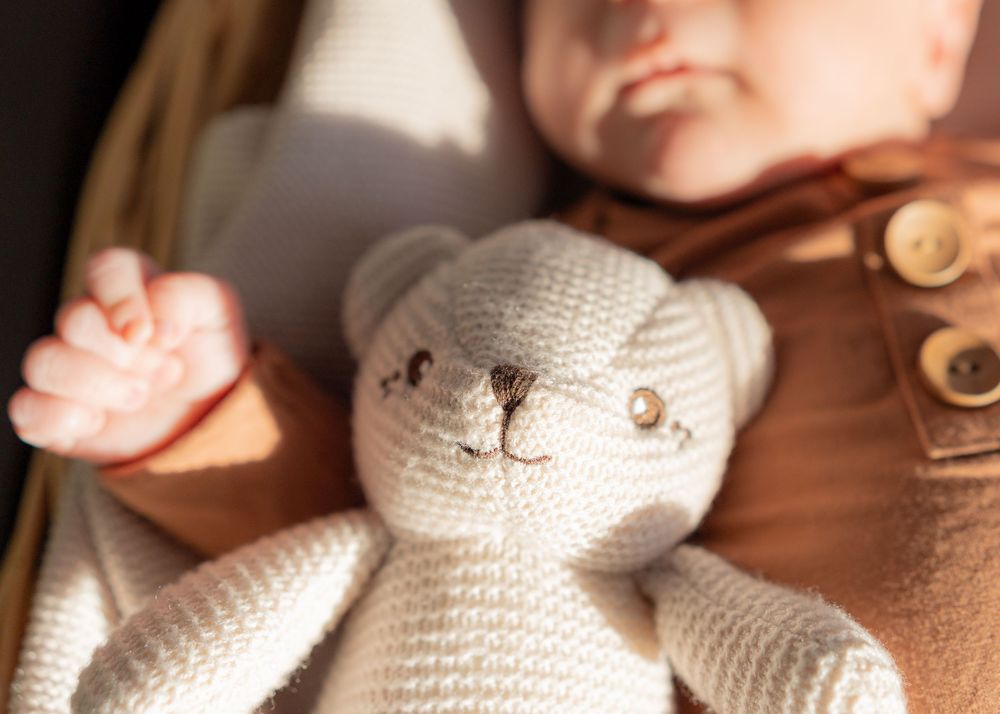 Close-up view of hands knitting a white yarn project with wooden needles in warm lighting.