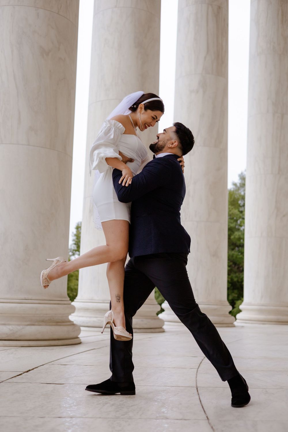 A romantic dip dance sequence between a couple in formal attire against white marble columns.
