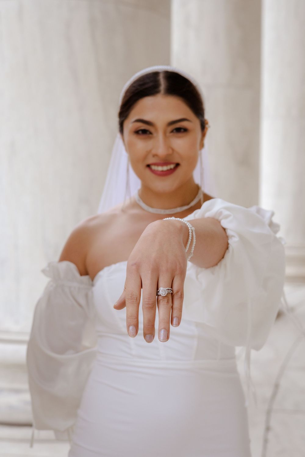 A series of four photos showing someone in white clothing displaying an engagement ring on their hand.