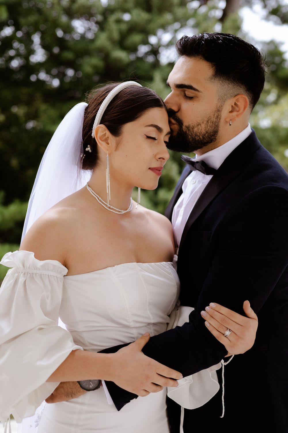 Romantic wedding couple sharing intimate moments in a garden setting with natural lighting.