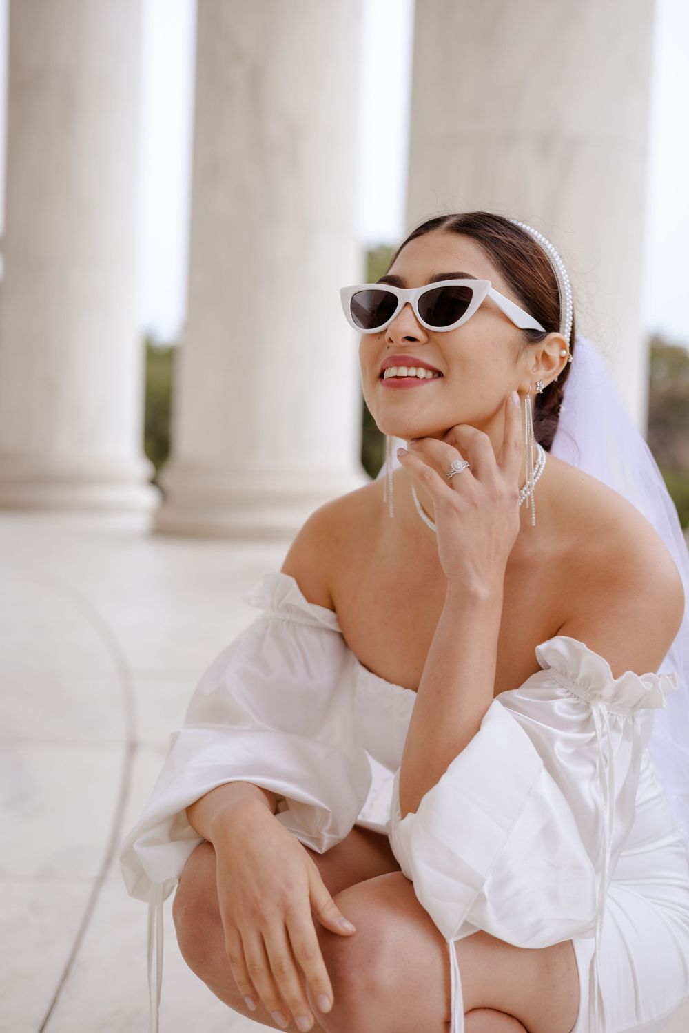 A fashion portrait series in white featuring retro sunglasses and an off-shoulder top against a bright architectural backdrop.