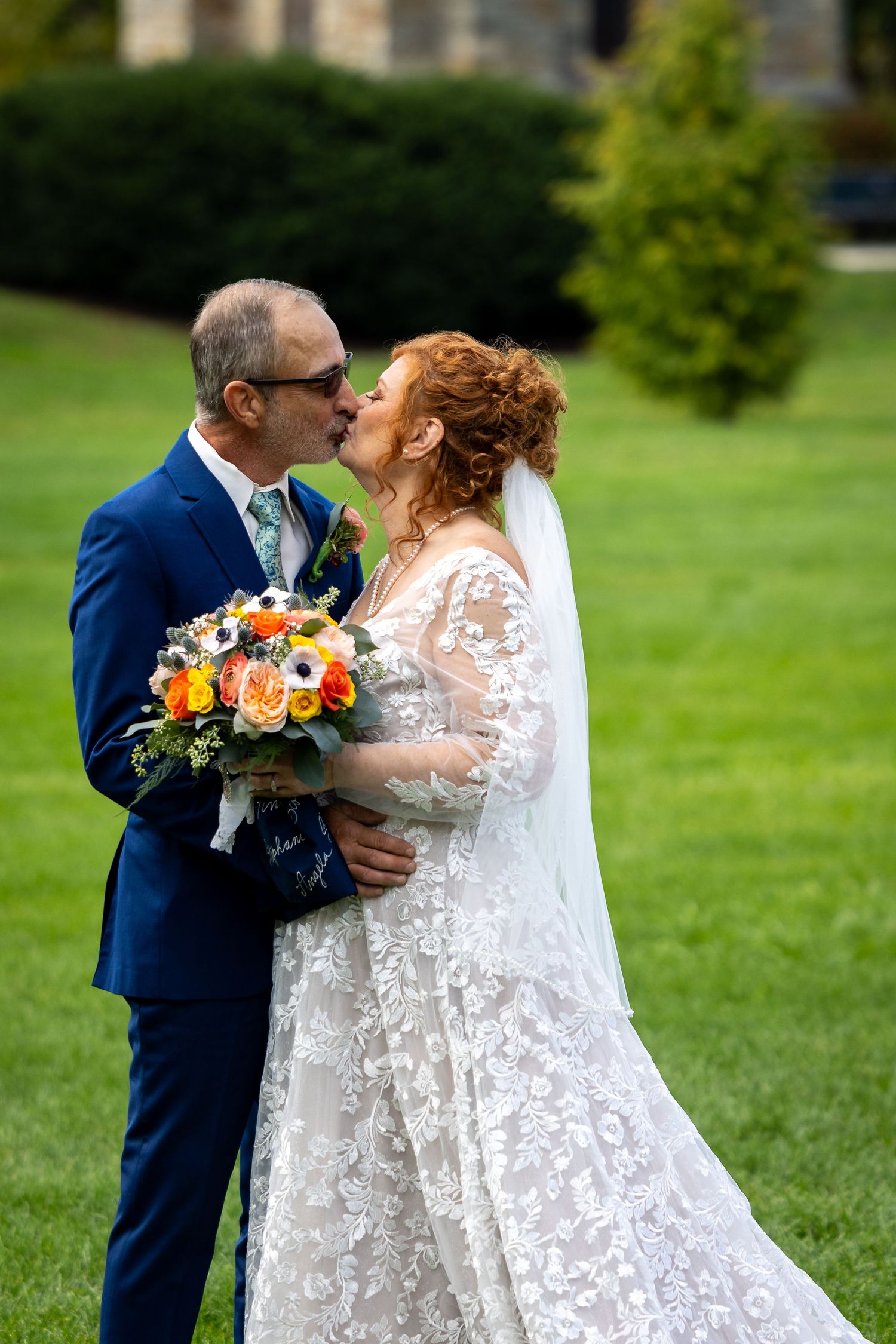 frederick maryland wedding photographer A romantic wedding moment captured on a green lawn with a beautiful floral bouquet.