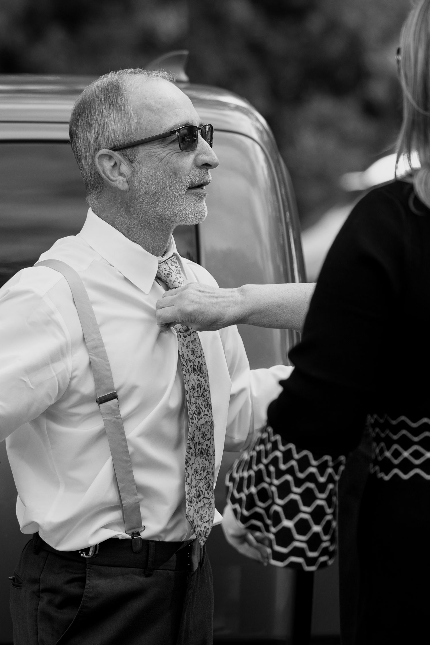 frederick maryland wedding photographer Black and white portrait of guest in formal attire with sunglasses and suspenders.