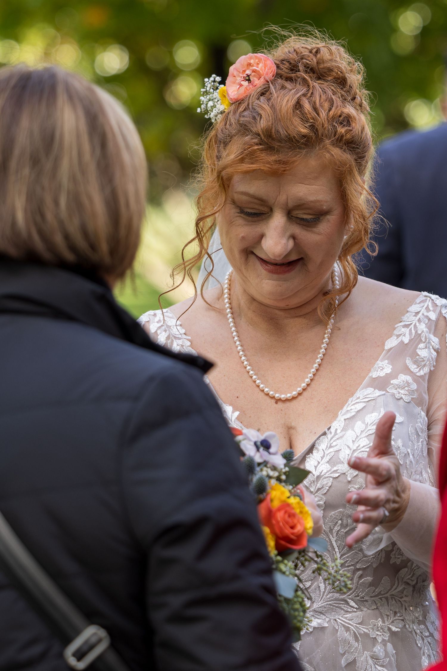 frederick maryland wedding photographer Wedding guest in lace dress and pearls shares joyful moment during outdoor reception.