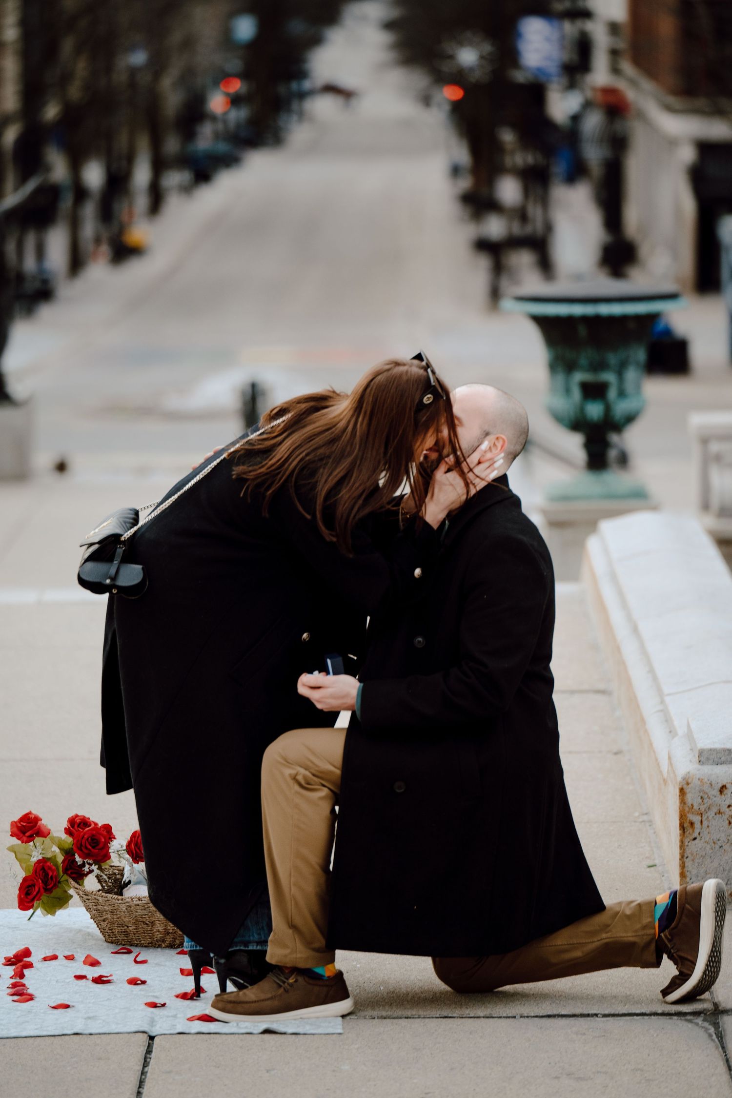 A series of five photos showing a romantic proposal moment on a city street with red rose petals scattered on the ground.