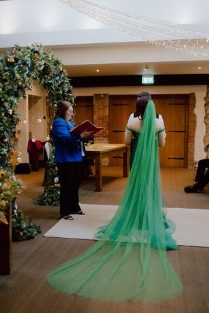 A sequence of photos showing someone adjusting a flowing emerald green tulle cape or train in an indoor venue.