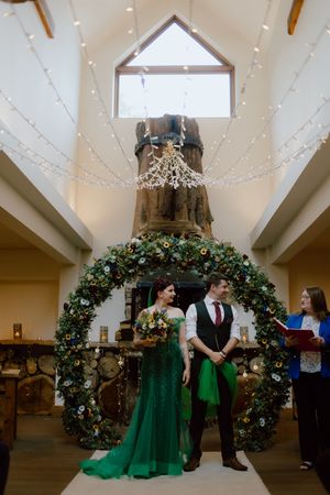 Wedding venue interior decorated with large floral archways and twinkling lights illuminating the vaulted ceiling.