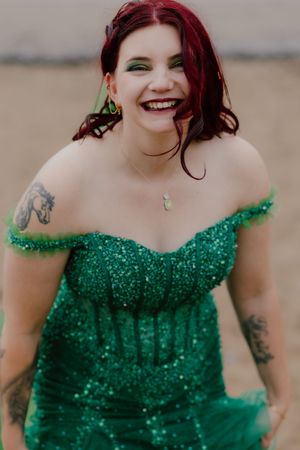 A woman in a sparkling emerald green off-shoulder gown smiles joyfully in a series of photos.