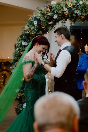 A couple shares a romantic first dance under a floral arch at their wedding reception.