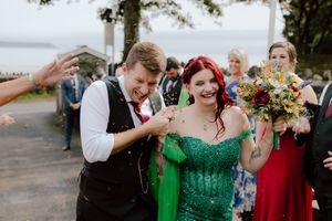 A group celebrates at an outdoor wedding wearing vibrant red and emerald green formal attire.