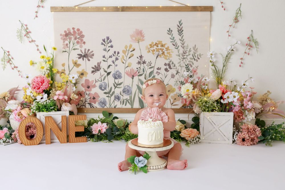 Floral photography backdrop with pink and peach flowers, cake display and rustic decor.
