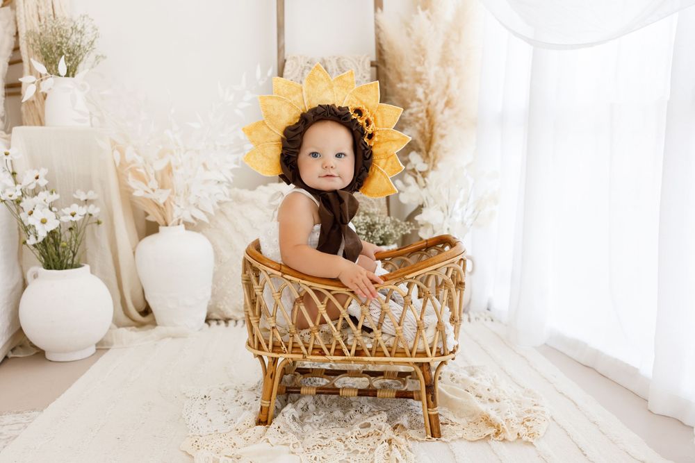 Artistic newborn portraits with vintage gold chair and white floral decorations.