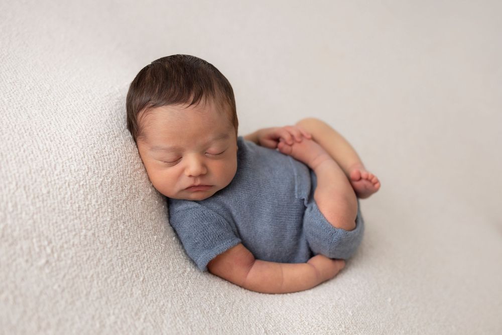 Professional newborn photography with minimalist grey and white styling.