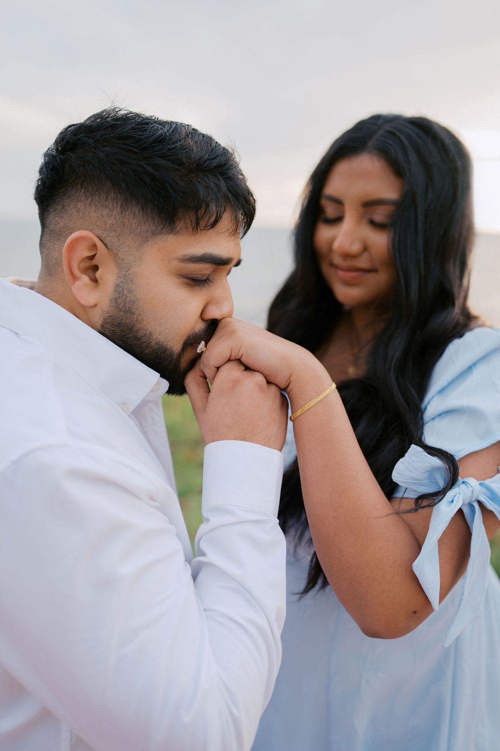 A romantic moment captured between a couple in light blue and white attire during an outdoor photoshoot.