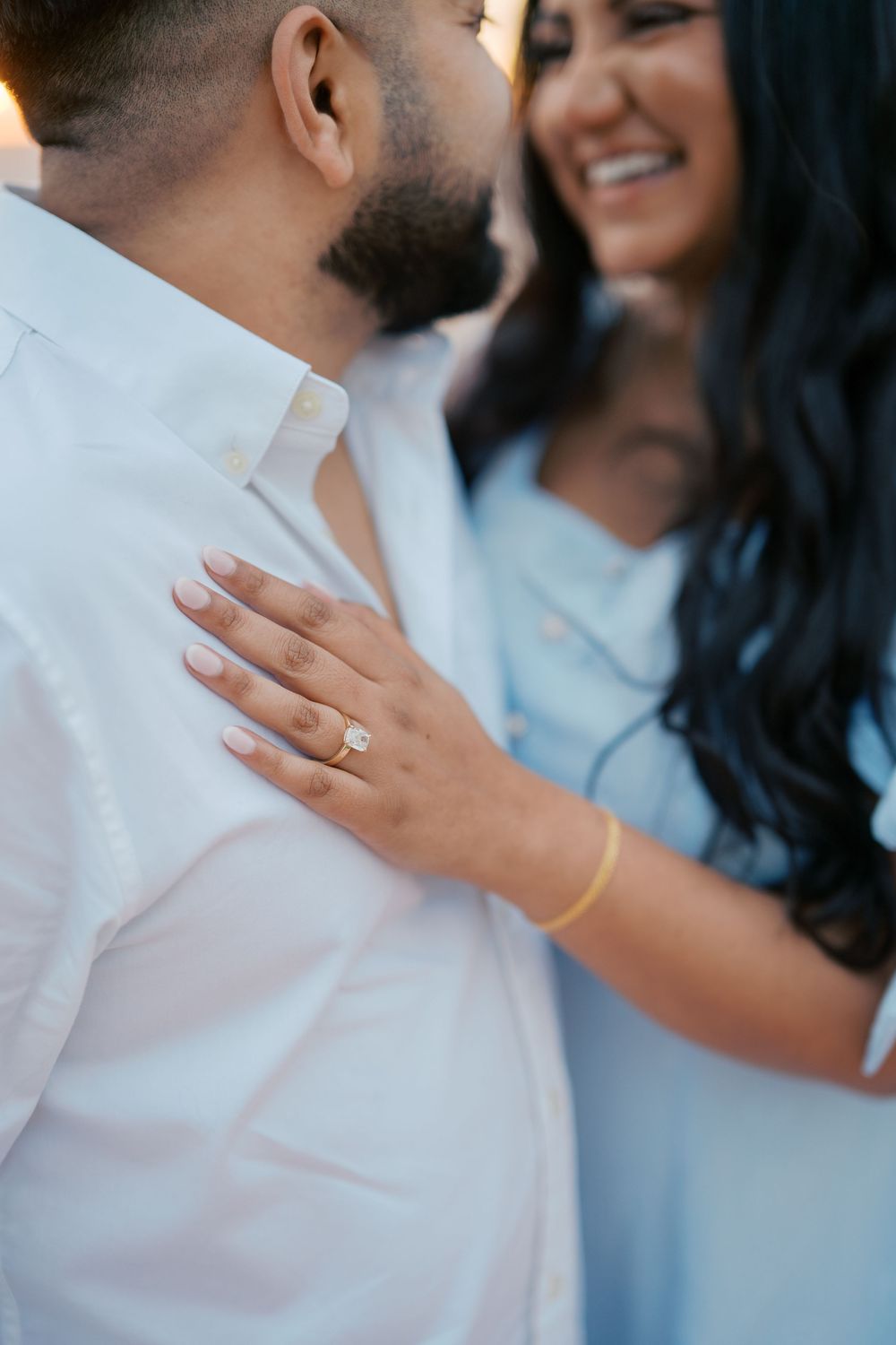 Close-up shots of hands and rings during a romantic beachside proposal moment.