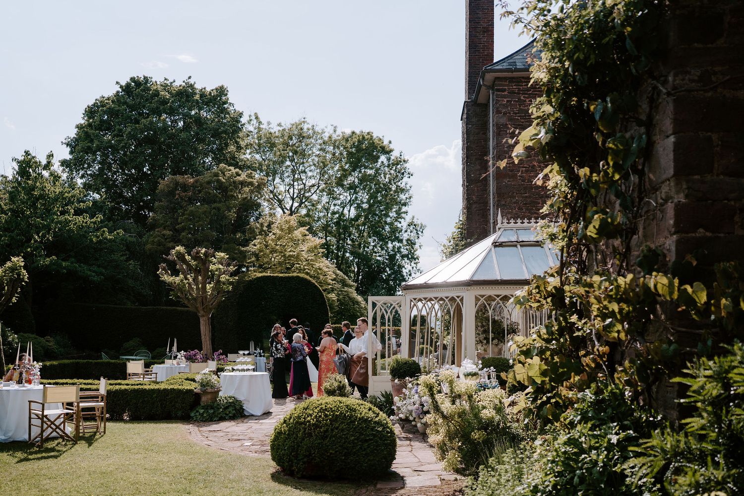 wedding guests enjoying drinks reception in the sunshine at dewsall court in herefordshire