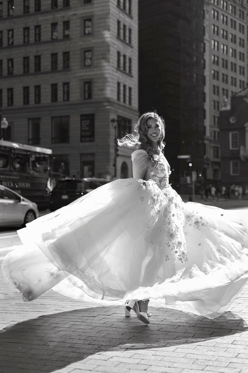 Bride twirling in a stunning white ballgown on a city street in a black and white wedding photo.