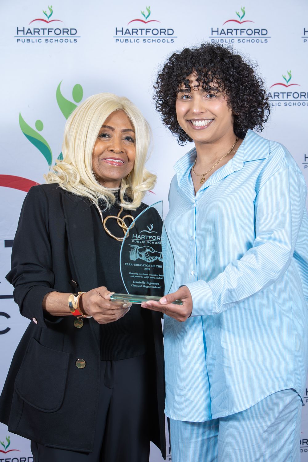 Two women pose together holding a Hartford Public Schools award plaque at an official recognition ceremony.