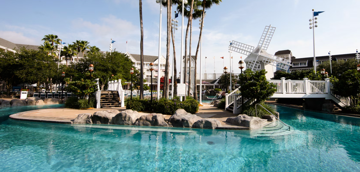 Resort swimming pool with tropical landscaping, palm trees and a lighthouse feature.