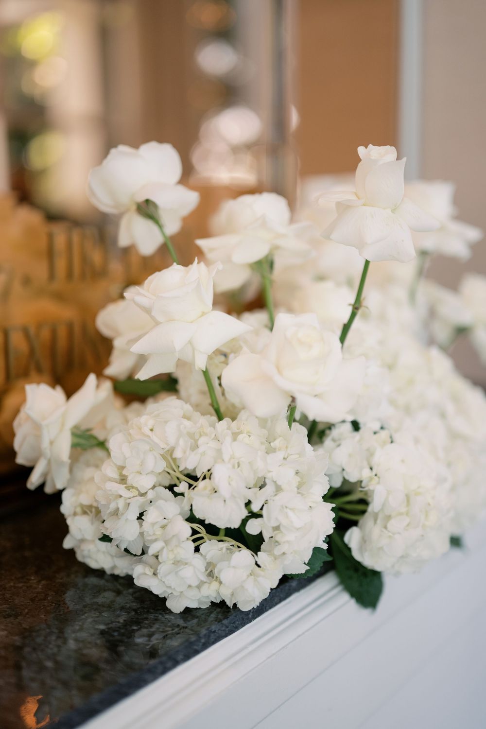 Elegant white rose and hydrangea wedding bouquet arrangement displayed on a marble surface.