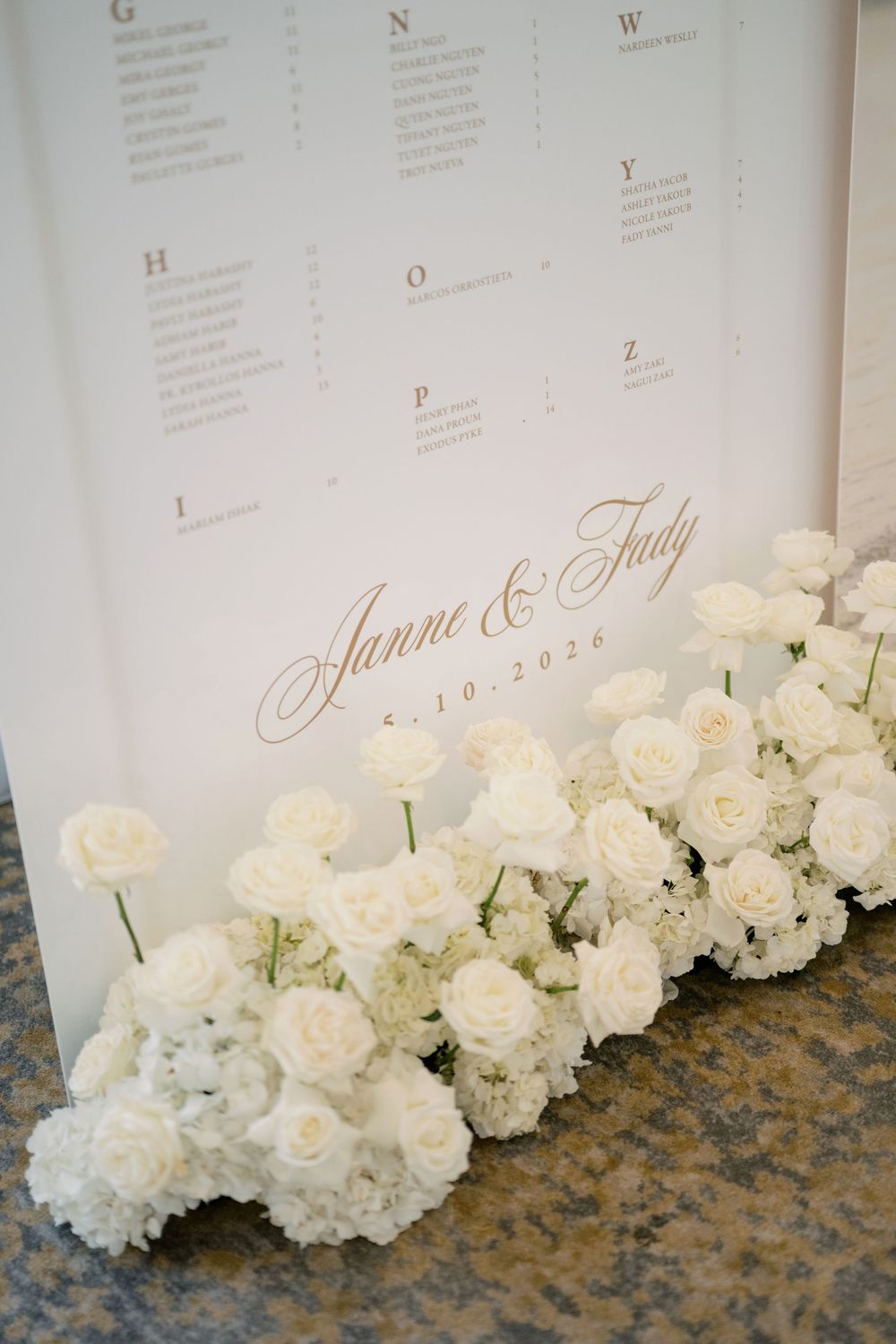 Wedding seating chart for Janne and Jady dated 5.10.2026 adorned with white roses at base.