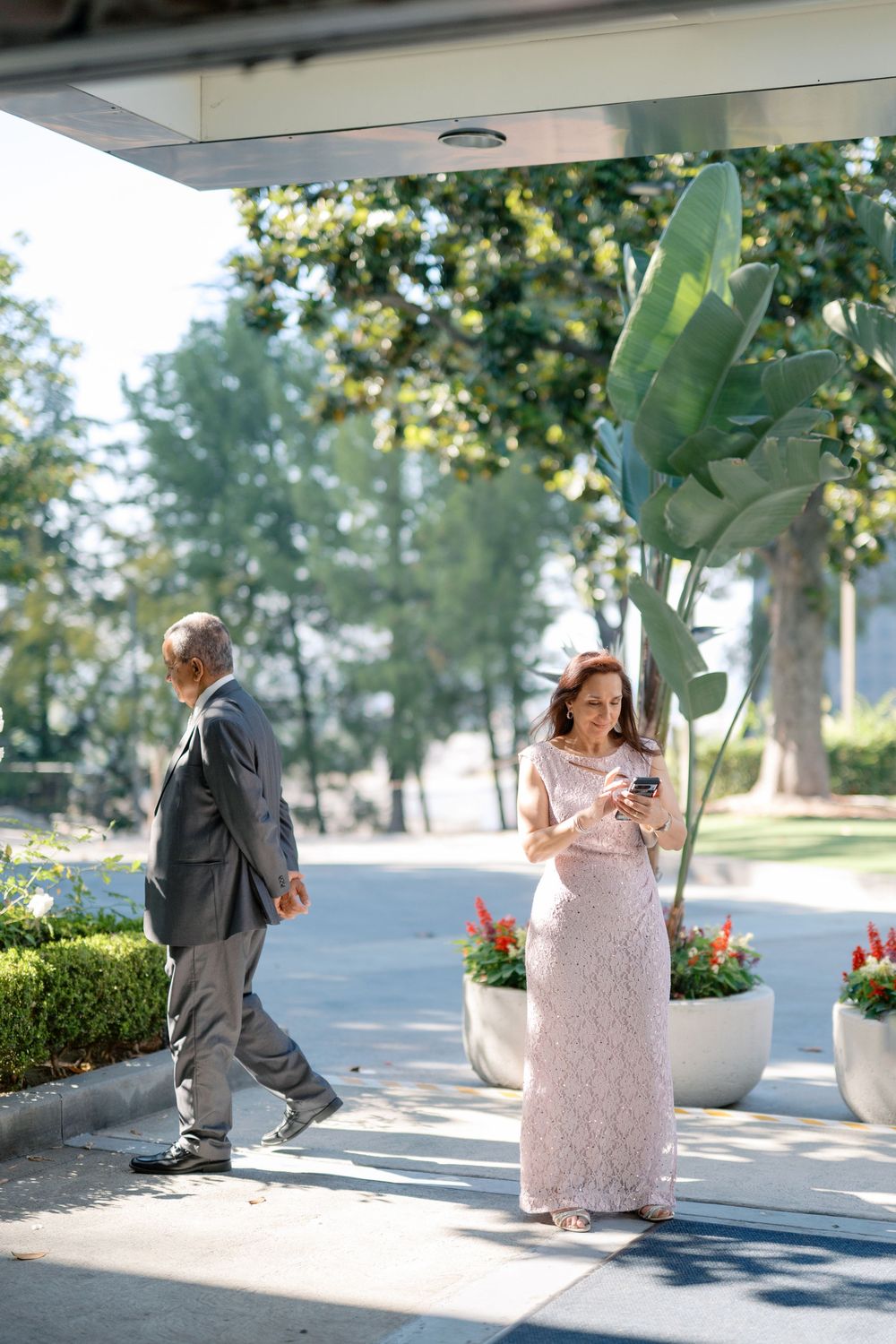 Wedding guests arriving at an outdoor venue entrance surrounded by tropical plants and greenery.