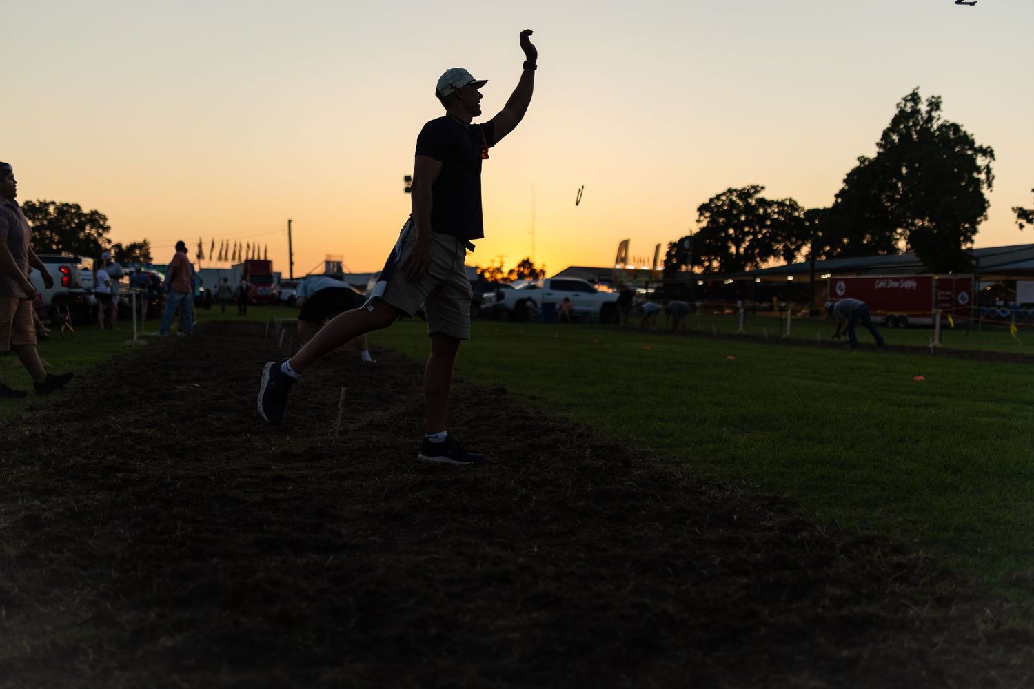 A hunter in jeans holds a German Shorthaired Pointer dog on a leash outdoors in a field.
