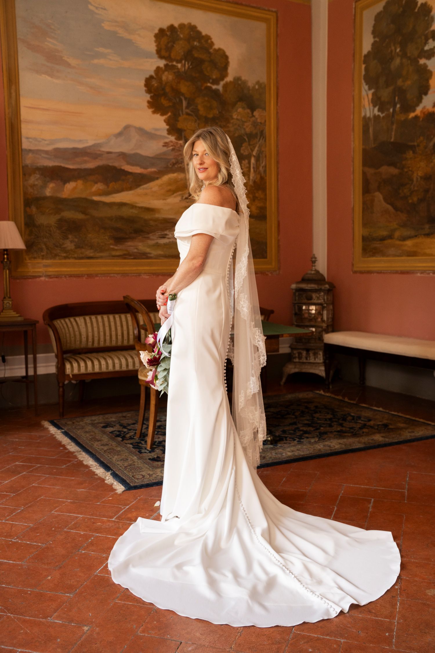 Joyful plus-size bride in white gown dancing under red stage lights at outdoor reception.