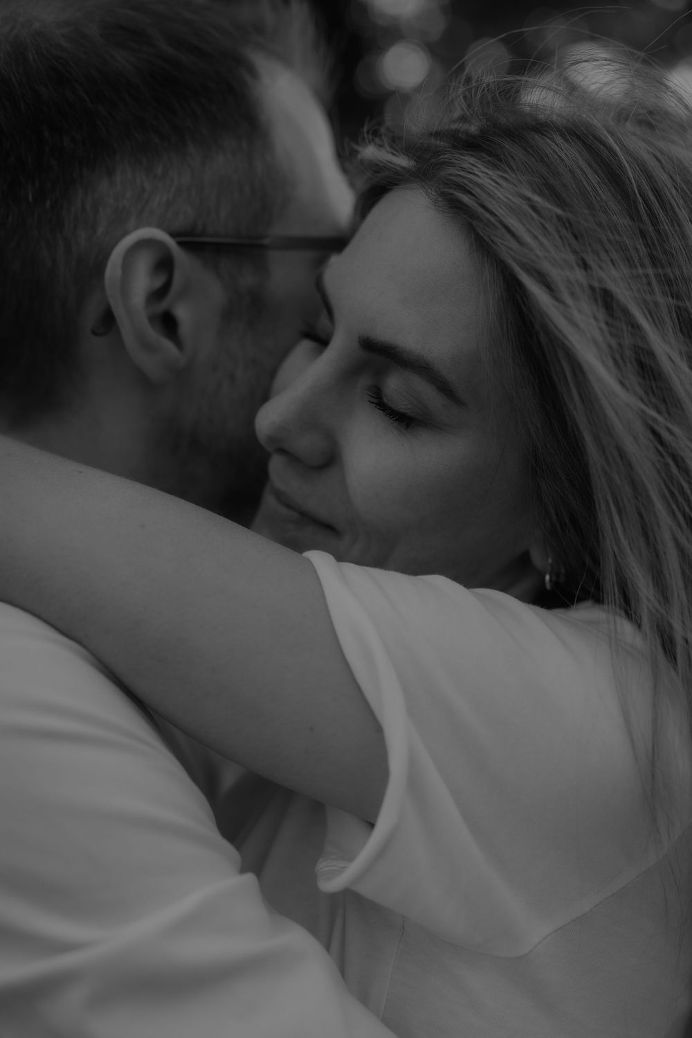 Black and white photo of a woman with closed eyes embracing a man in a tender hug.