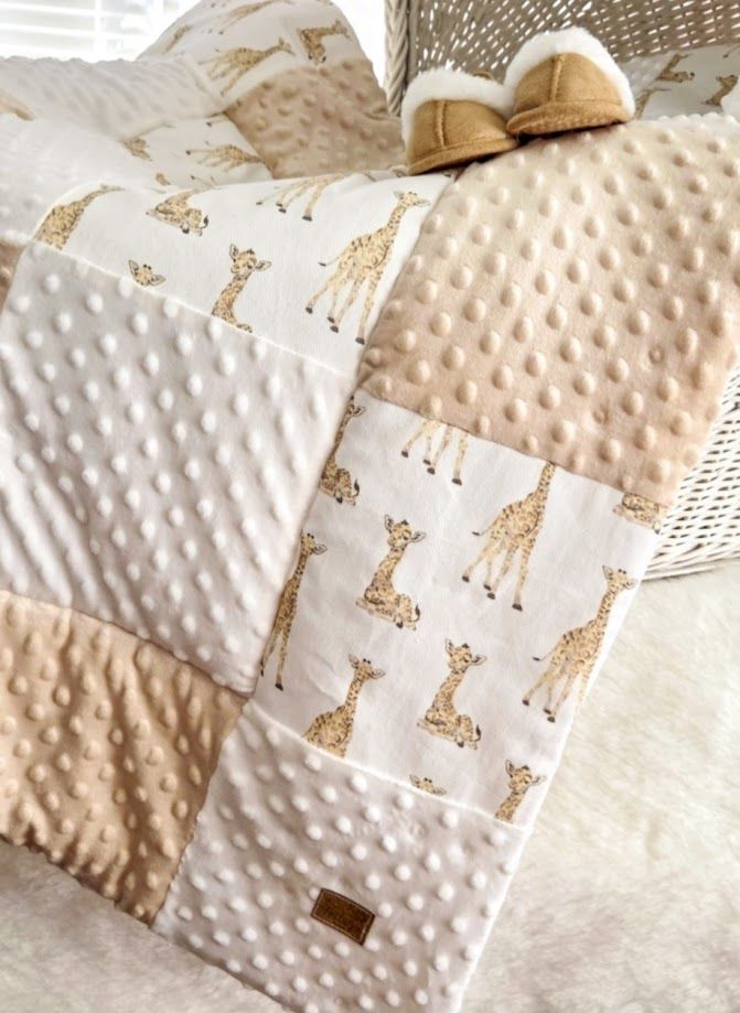 Pink and white patchwork baby quilt with minky dots, floral accents, and matching accessories on a white bed.