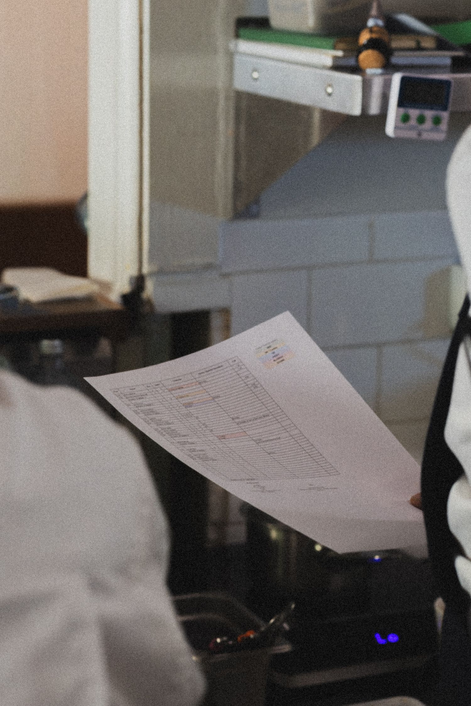 Chef reviewing a printed order sheet in a professional kitchen environment.